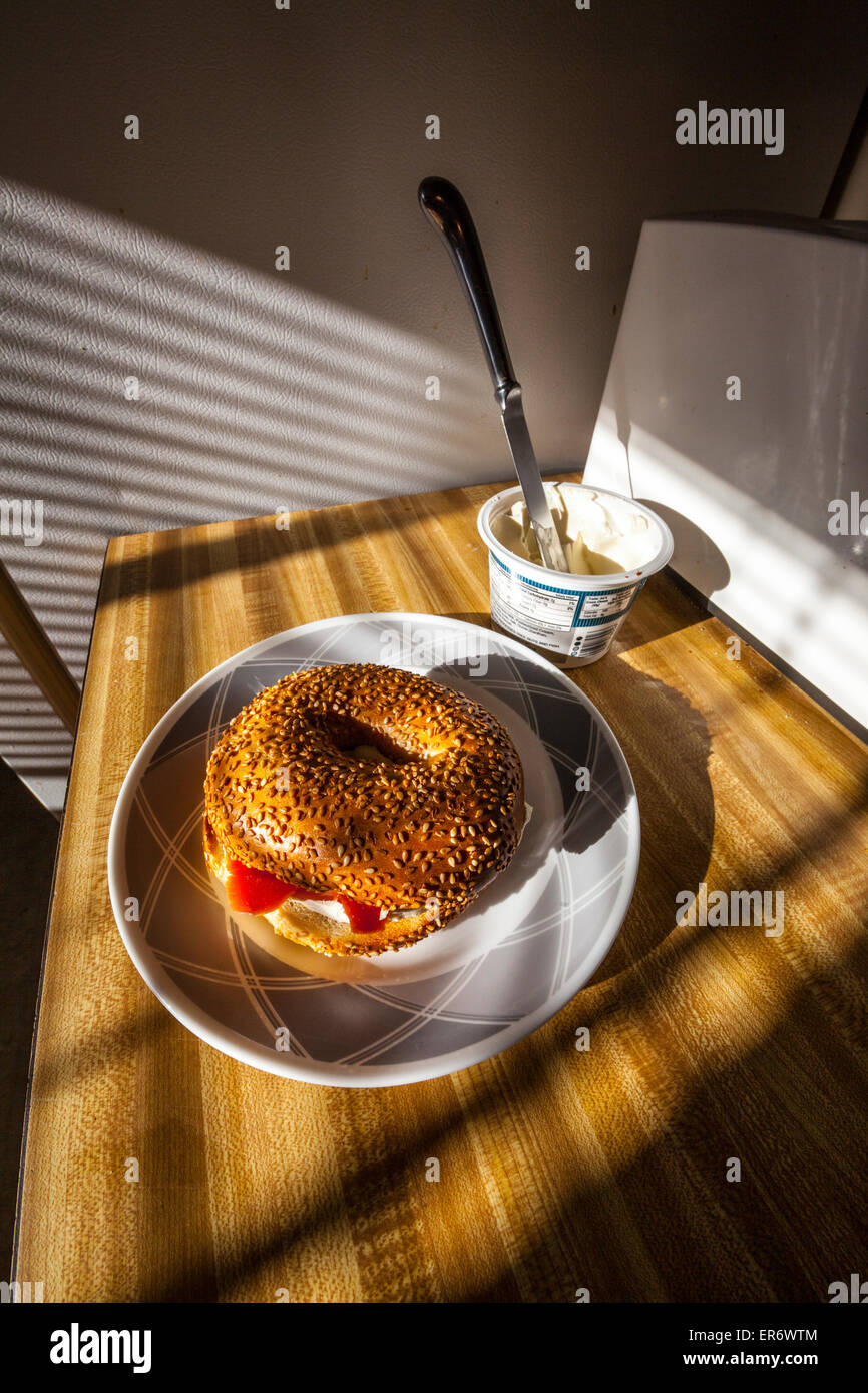 A sesame seed bagel with cream cheese and smoked salmon in the early