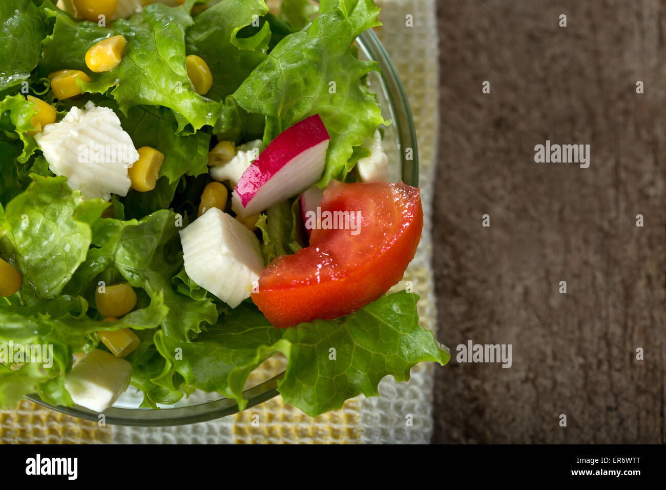 Fresh salad with corn and cheese in bowl over wood background Stock Photo