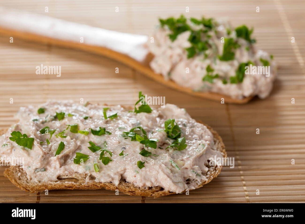 Fresh pate with bread on bamboo rug with one spoon in back Stock Photo