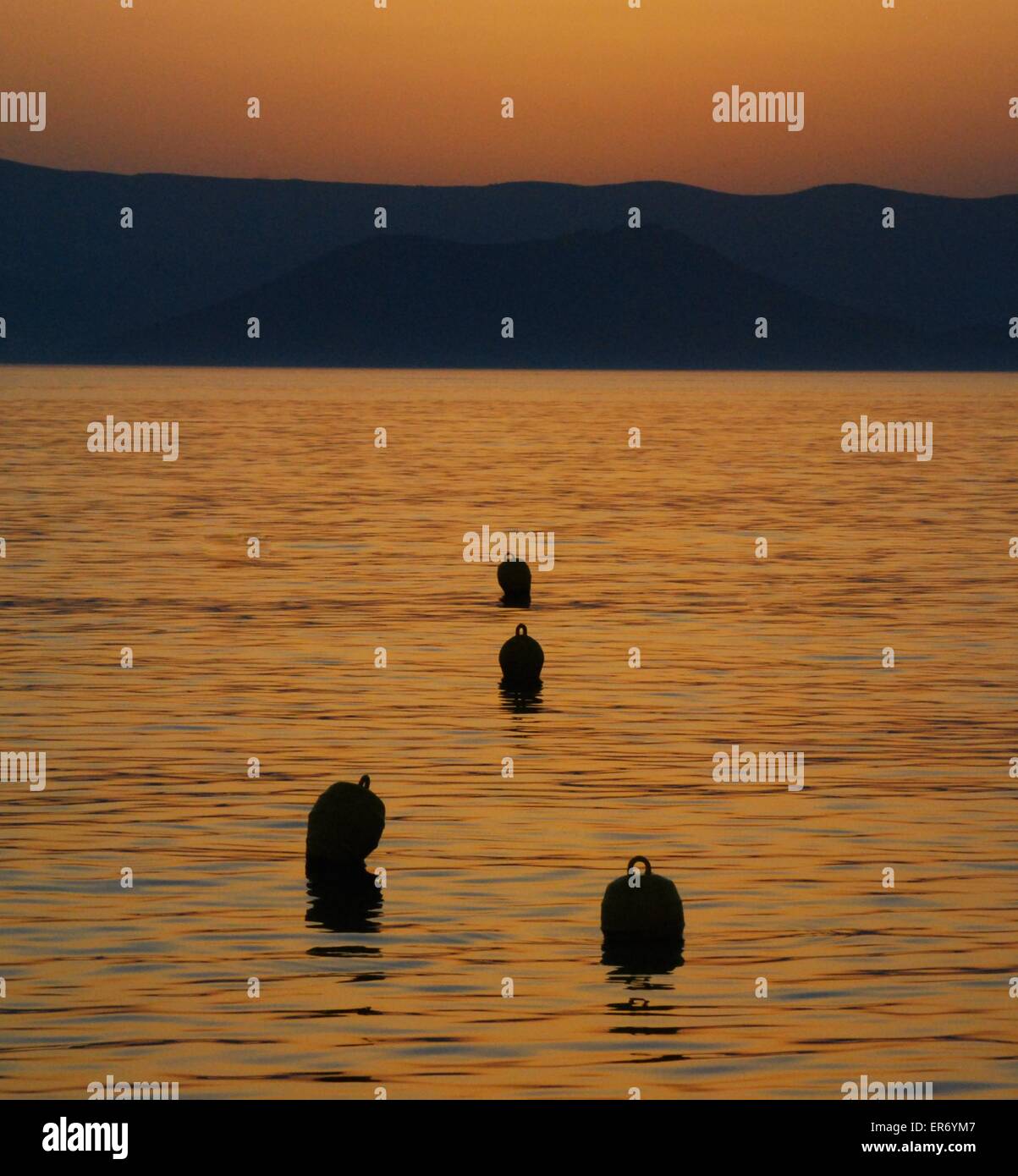 Marker buoys floating in the shimmering light of a glowing orange sunset Stock Photo