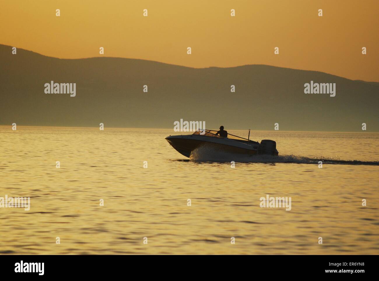 Powerboat speeding into the sunset on the Greek island of Naxos Stock Photo