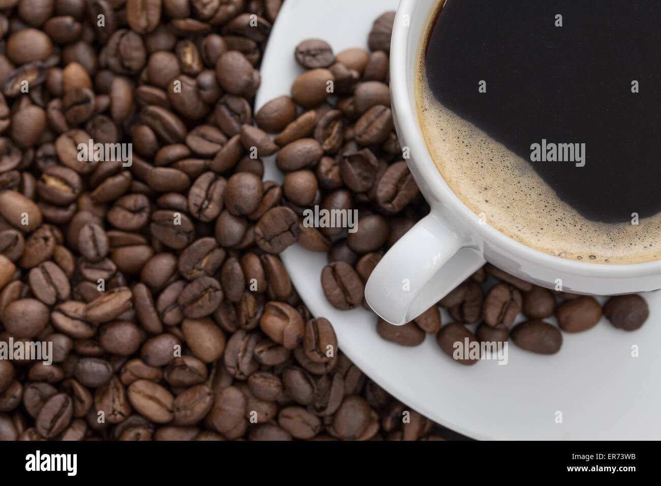 White coffee cup with coffee and around the cup lies coffee beans Stock Photo