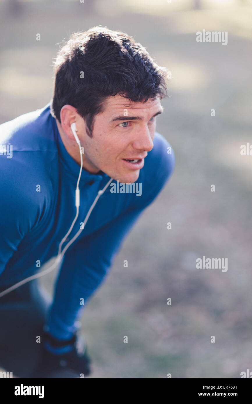 A young man prepares to jog in a park. Stock Photo