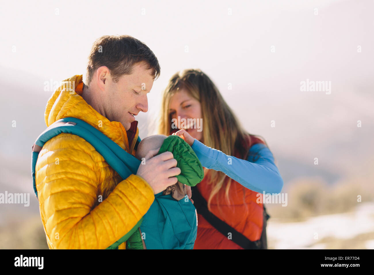 A young couple and their baby hike in the wintry mountains. Stock Photo