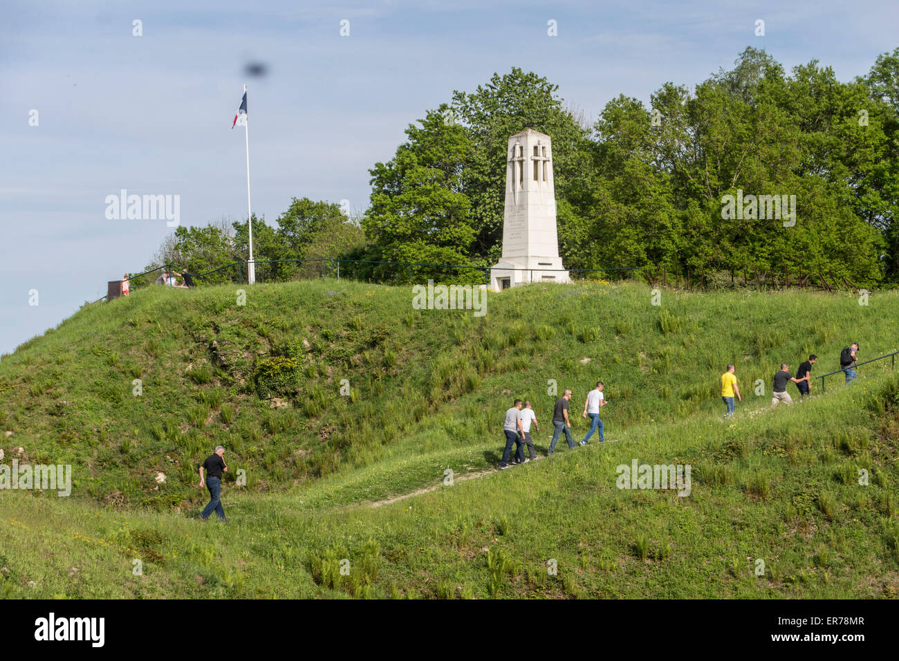 Vauqouis, France. People passing through large craters, created by underground mines during WW1. French flag and a battle memorial on top of the hill. Stock Photo