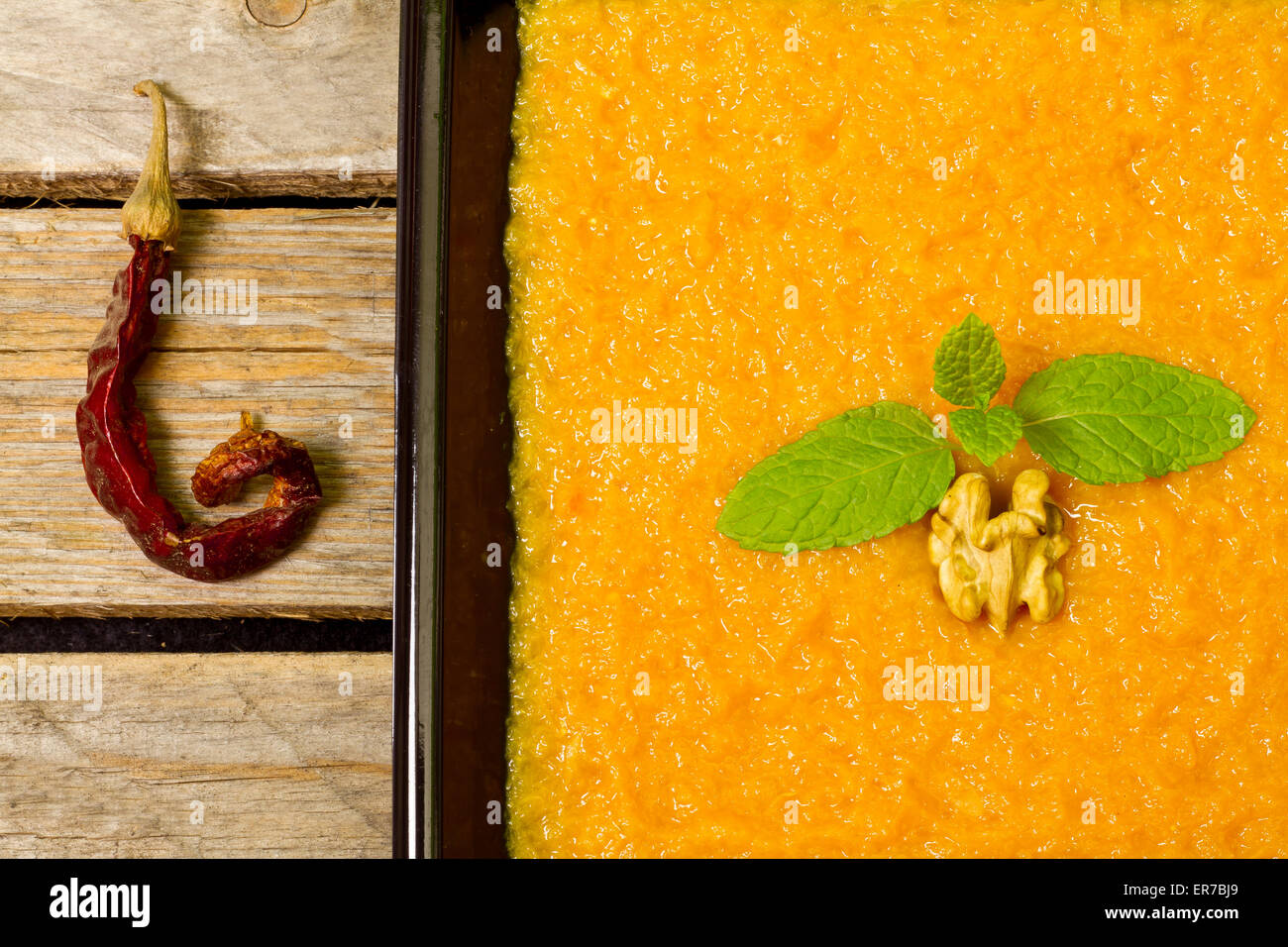 Pumpkin puree on a black plate decorated with mint, walnut and chilli Stock Photo