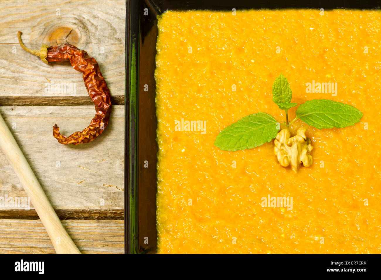 Pumpkin puree on a black plate decorated with mint, walnut and chilli Stock Photo