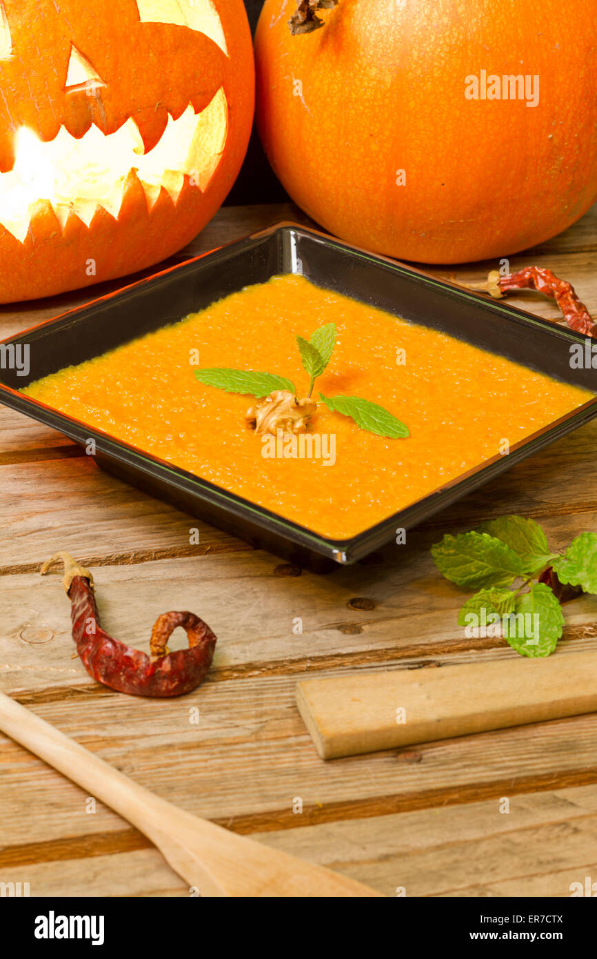 Pumpkin puree on a black plate decorated with mint, walnut and chilli Stock Photo