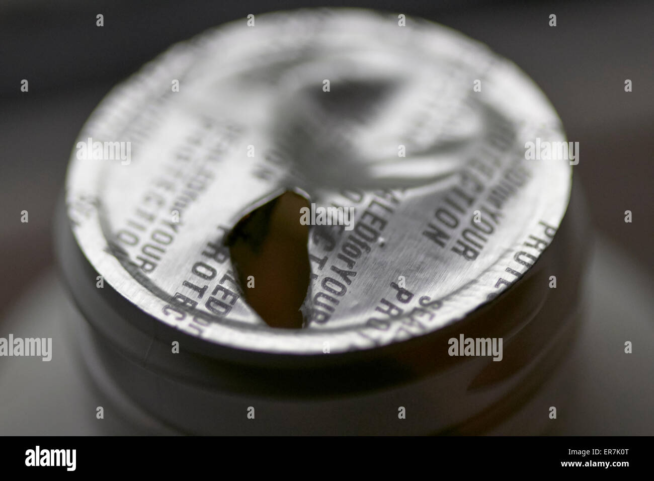 broken tampered with foil sealed tamper proof top on a bottle of pills