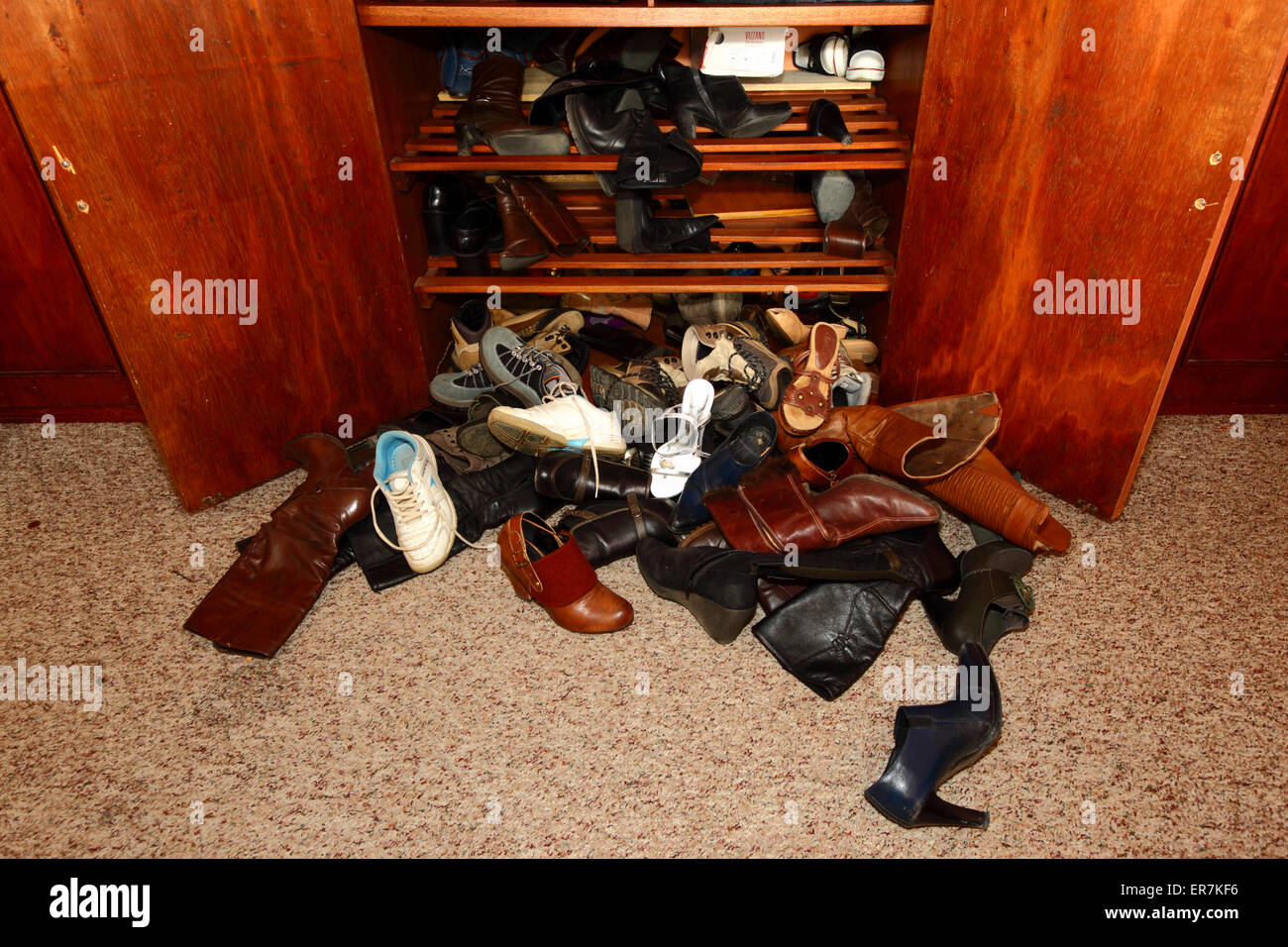 Selection of womens shoes scattered untidily on floor in front of wardrobe in bedroom Stock Photo