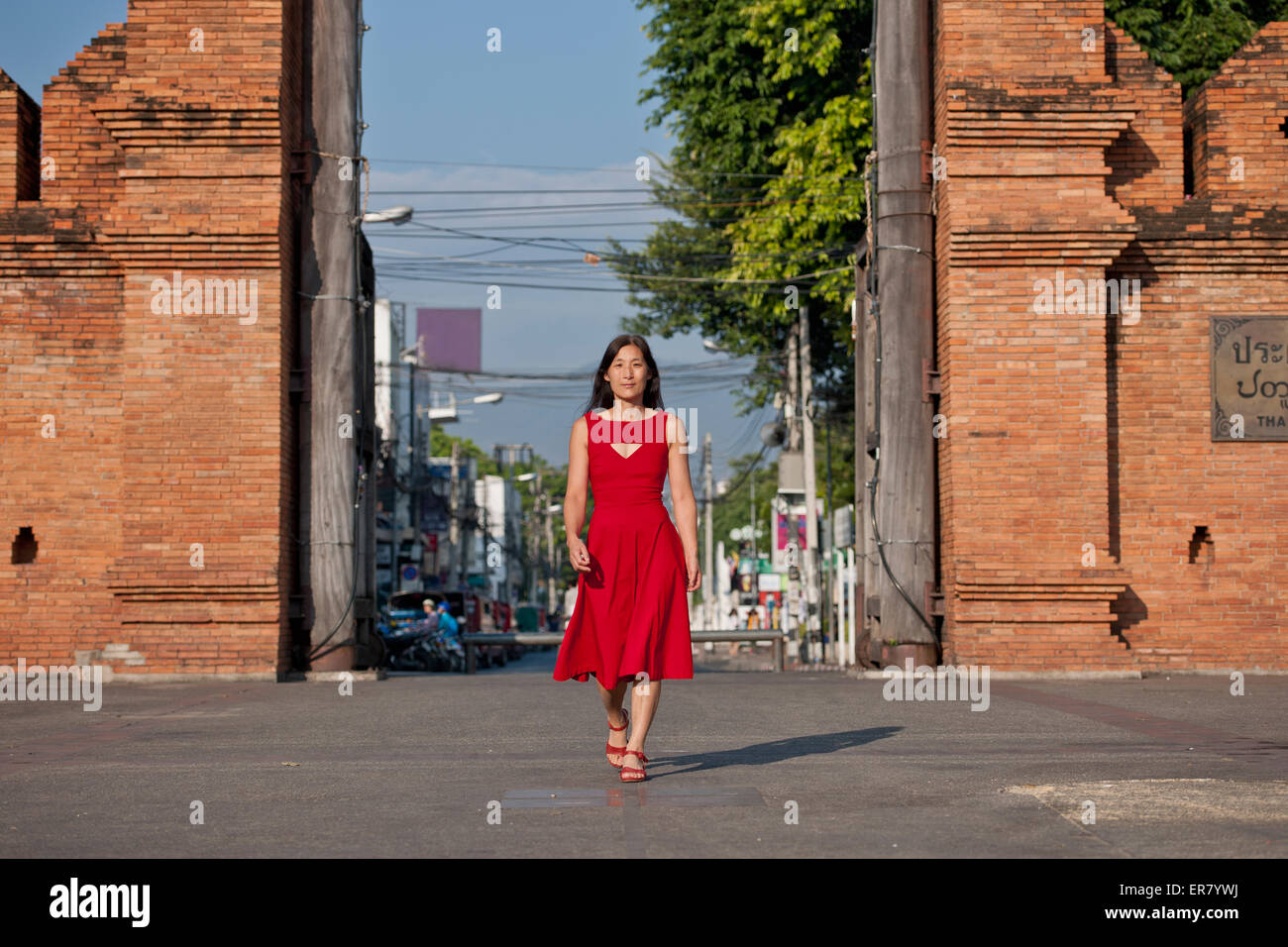 woman in red dress walking at the old city gate in Chiang Mai in northern Thailand Stock Photo