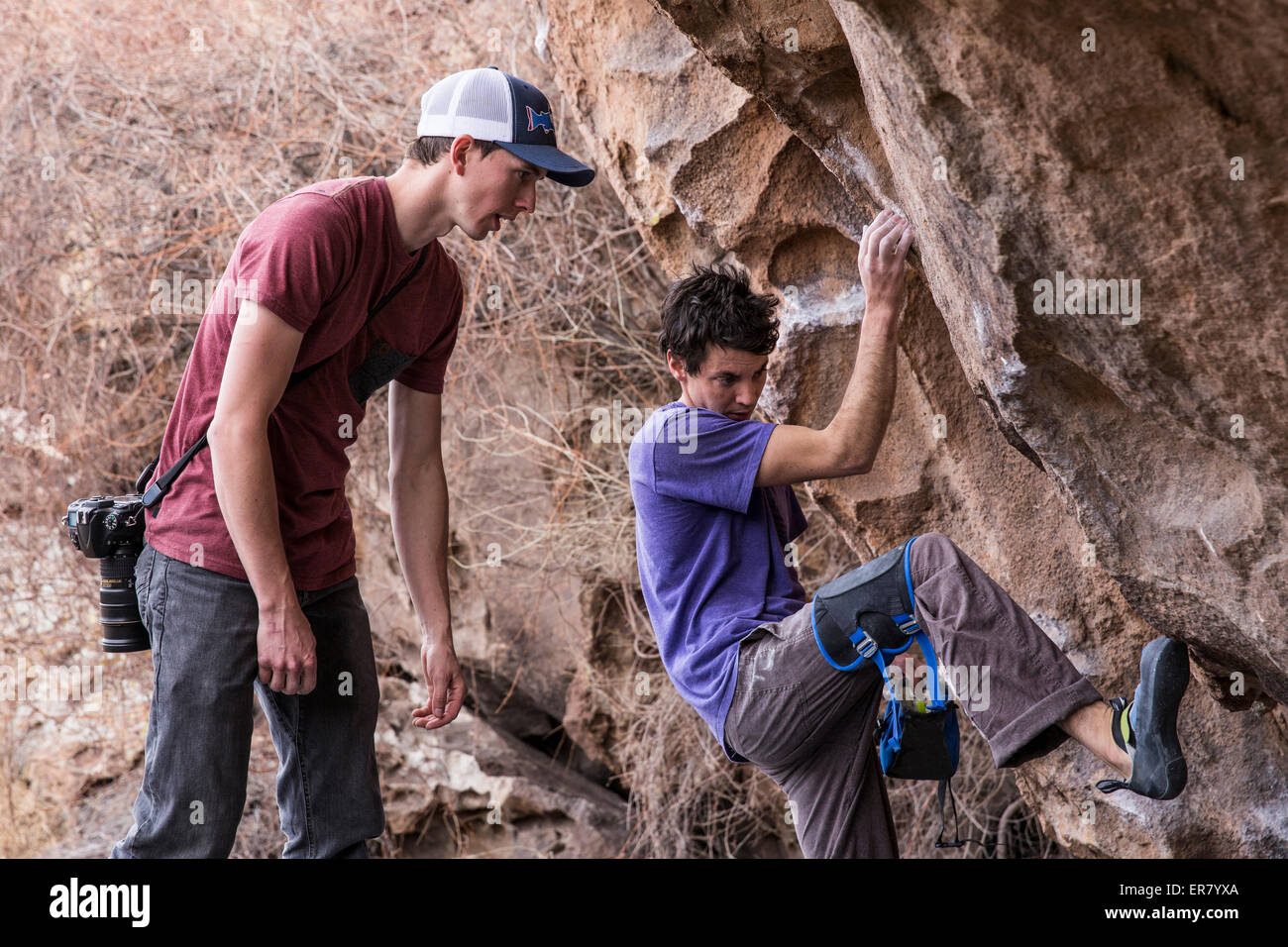 Rock climber figuring out the best way to climb the boulder in Hueco Tanks State Park, Texas Stock Photo