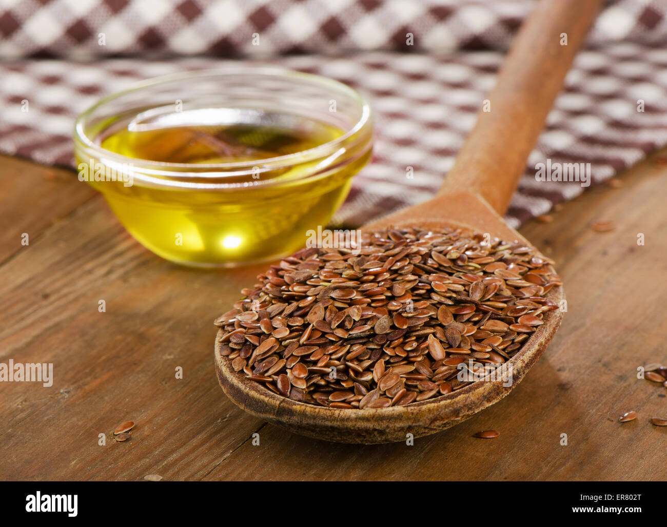 Brown flax seeds on a spoon and flaxseed oil on wooden table Stock Photo -  Alamy