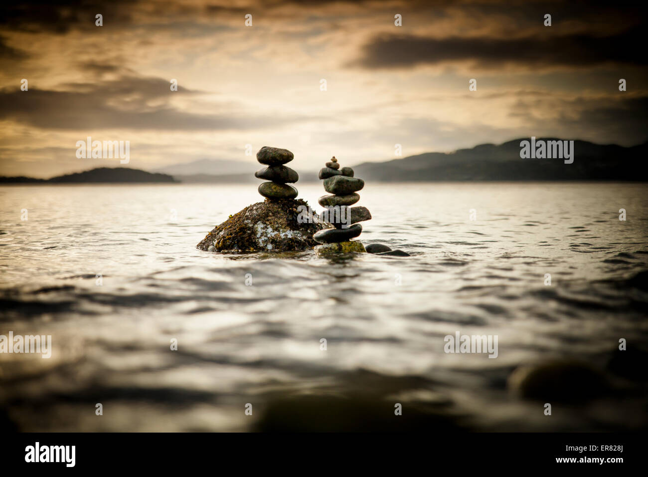 Two small rock stacks are built near the shore of a beach in Sechelt, Canada. Stock Photo