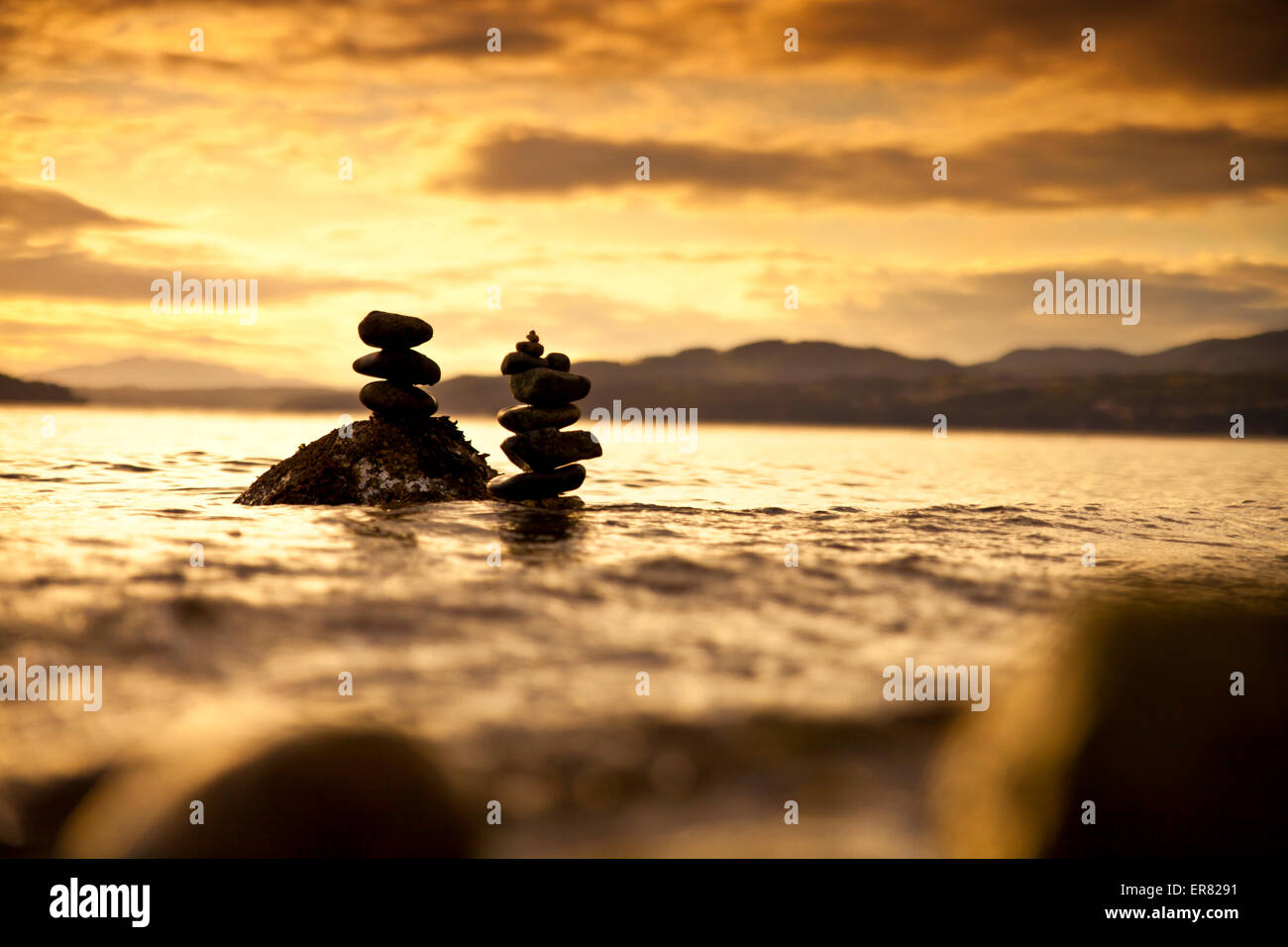 Two small rock stacks in the water at sunset Stock Photo - Alamy