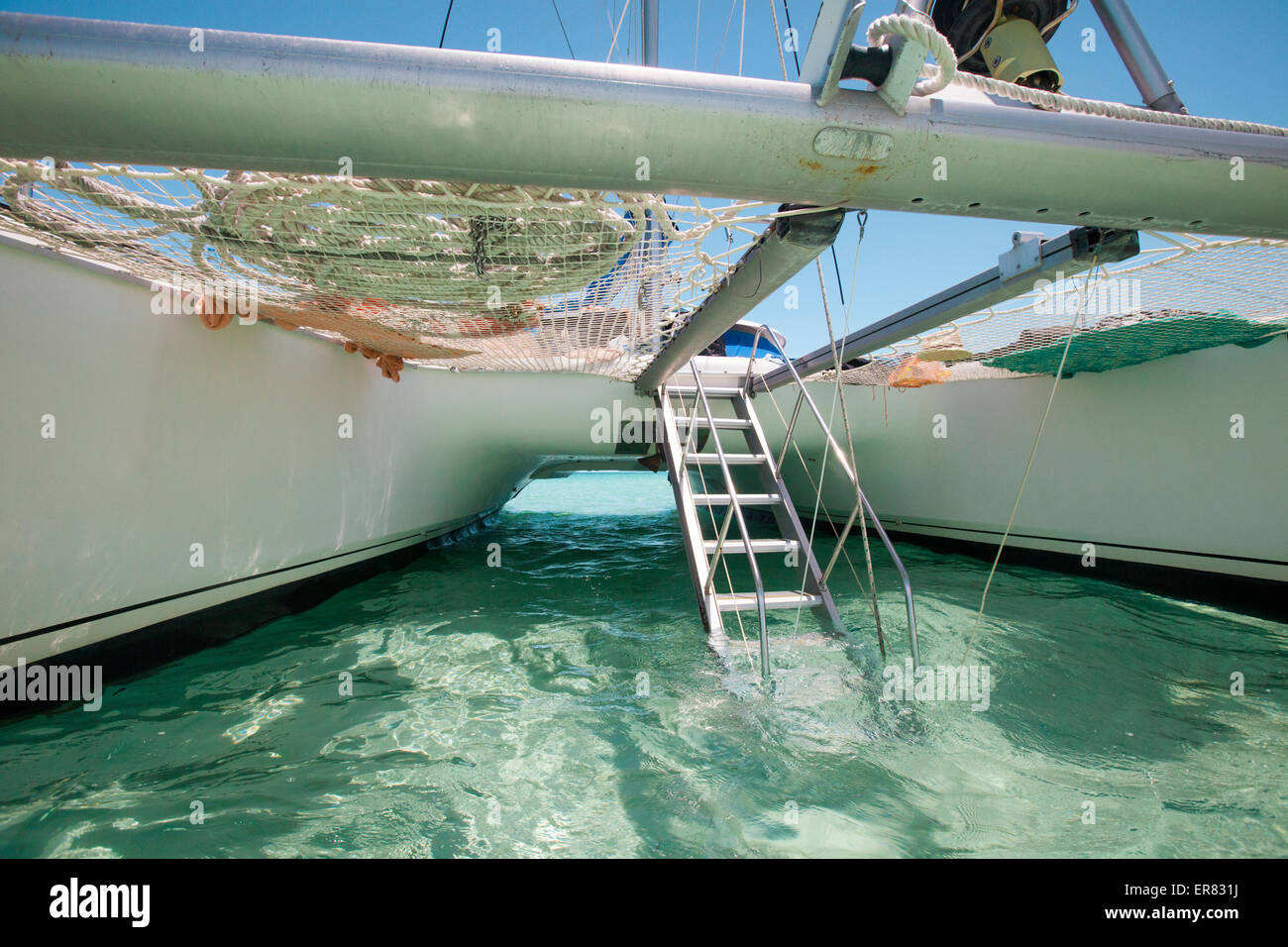 A drop-down aluminum staircase leads up to the deck of a catamaran boat. Stock Photo