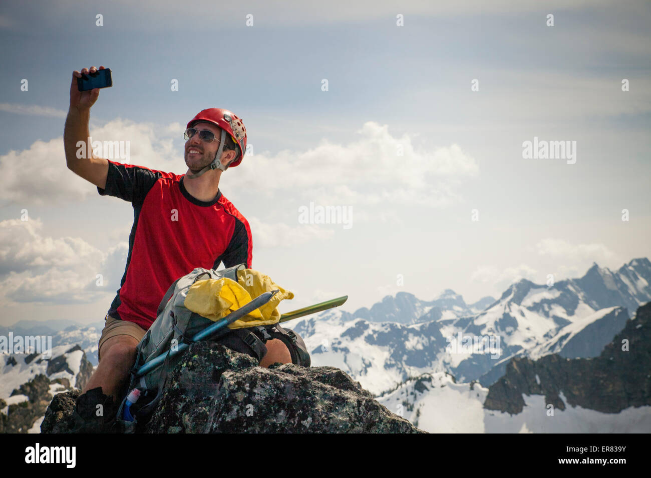 A climber takes a selfie with his smartphone from the summit of Trio Peak. Stock Photo