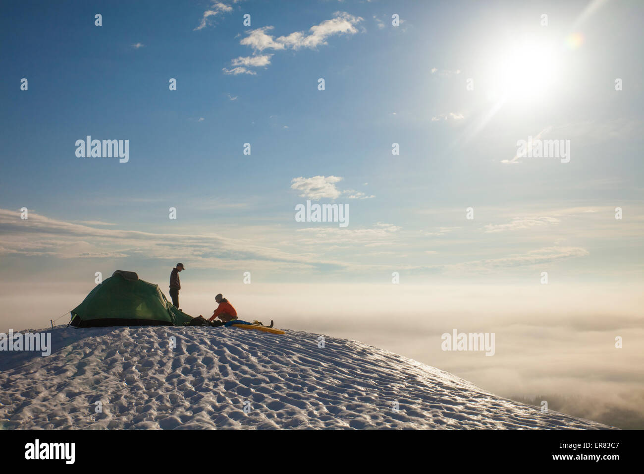 Two climbers sort their gear out beside their tent while camping. Stock Photo