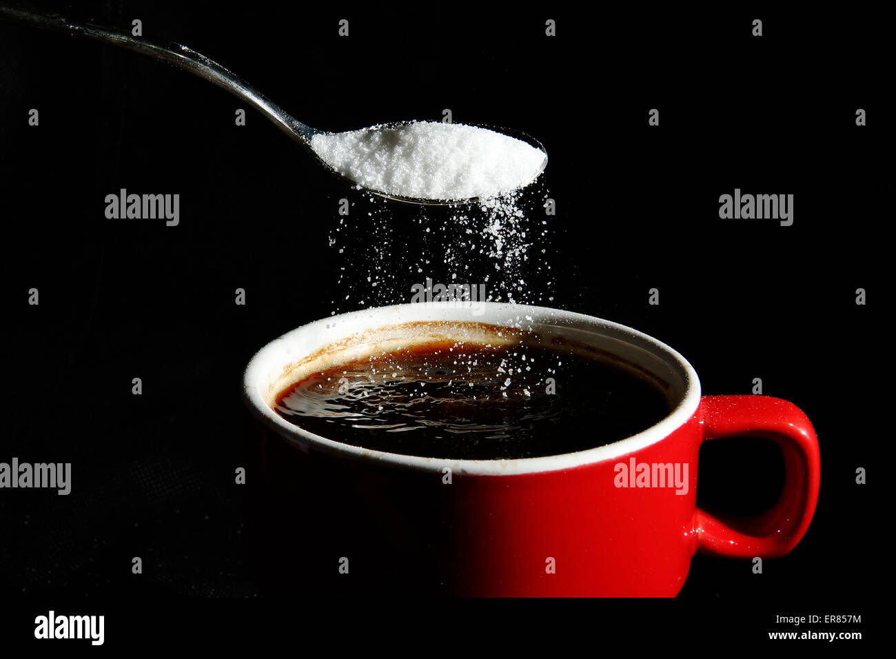 A spoonful of sugar is poured into a cup of coffee Stock Photo
