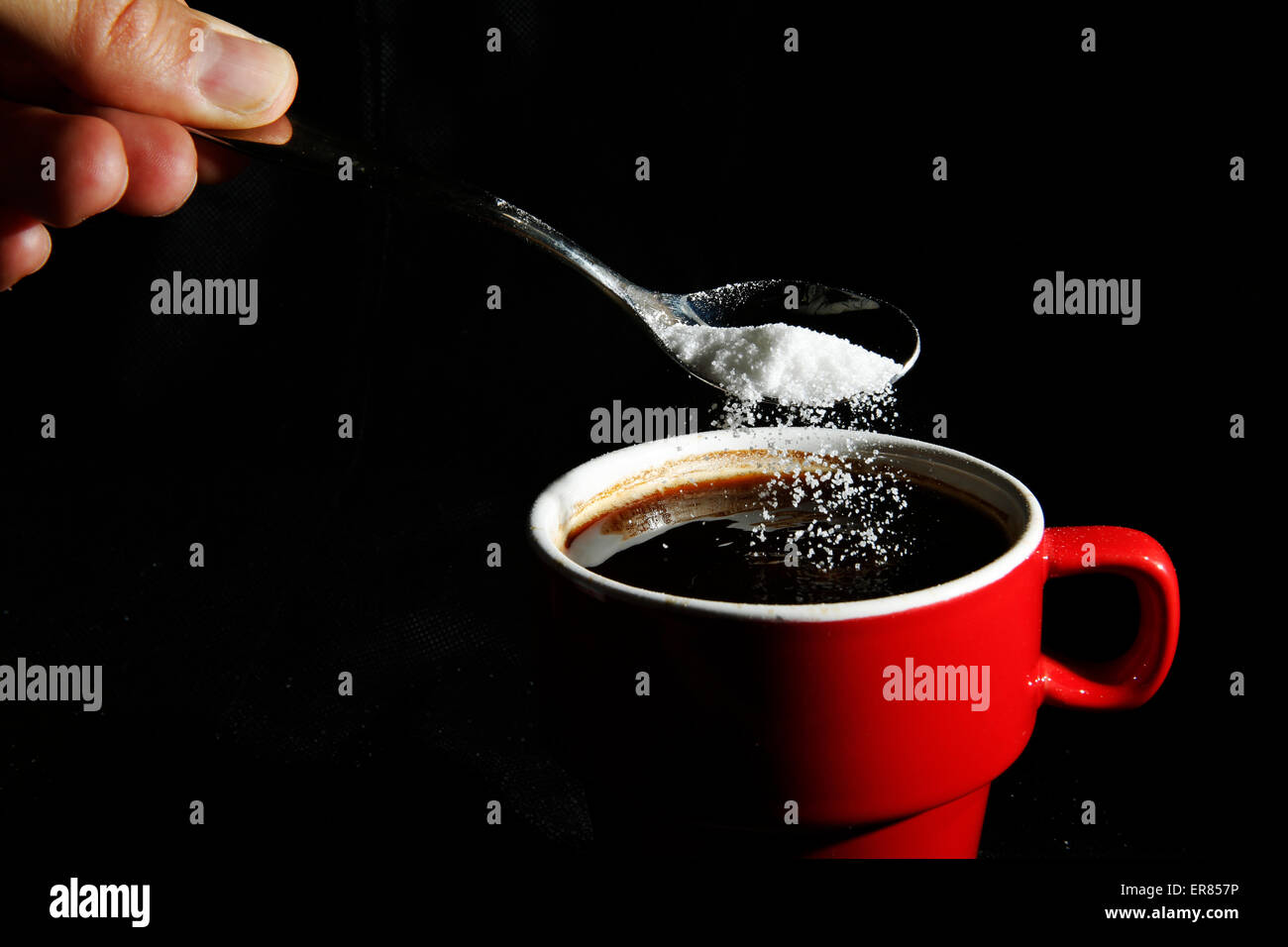 A spoonful of sugar is poured into a cup of coffee Stock Photo