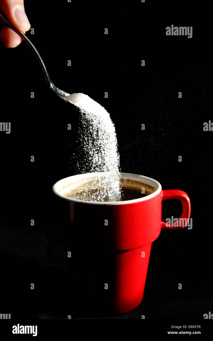 A spoonful of sugar is poured into a cup of coffee Stock Photo