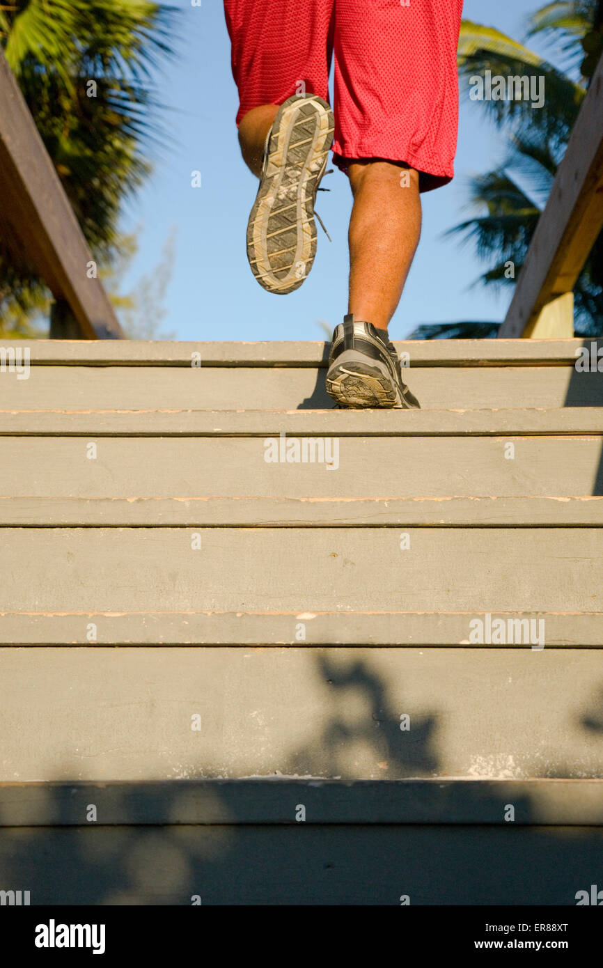 A man's legs as he runs up stairs Stock Photo