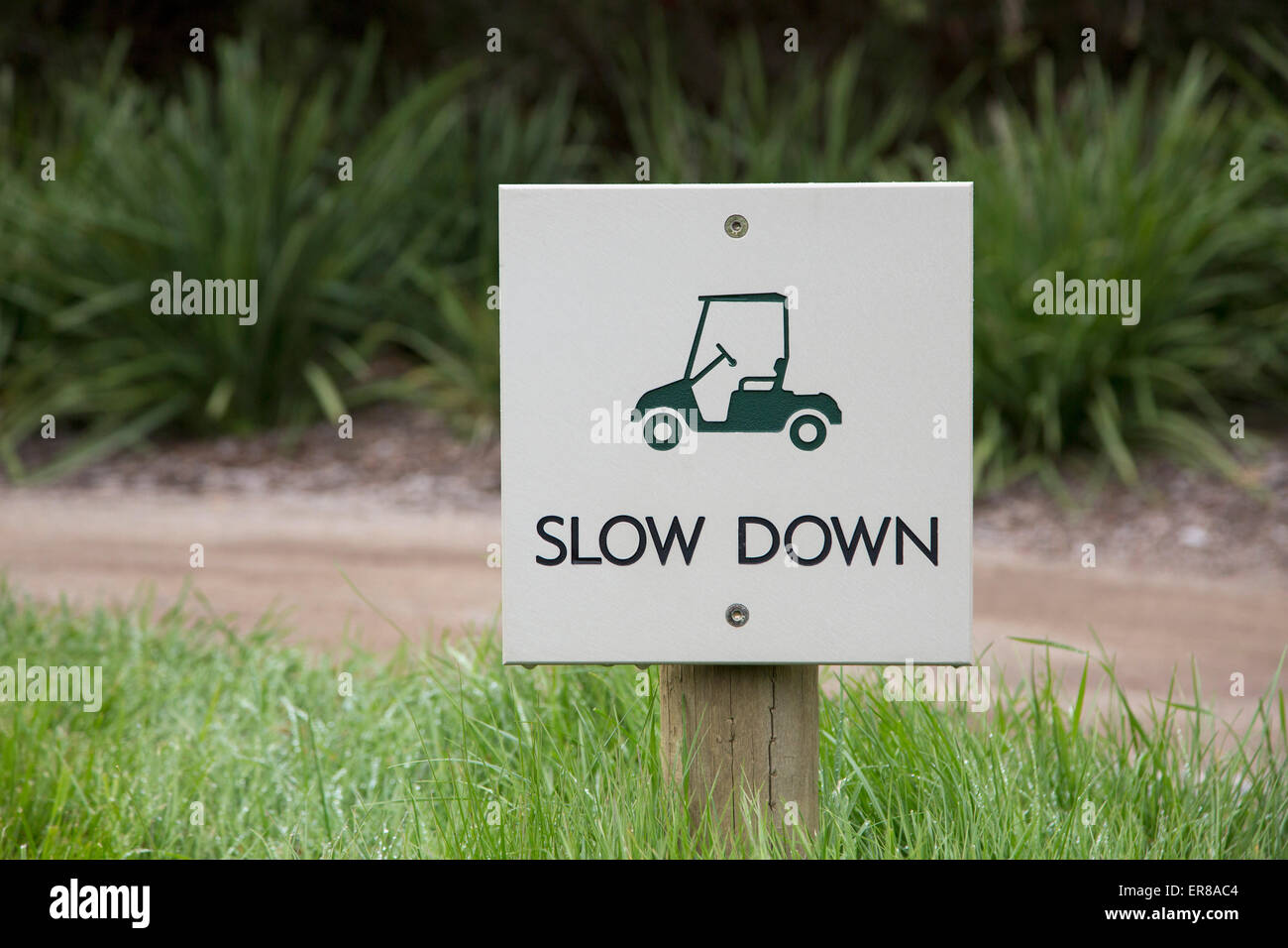 Slow down warning sign on field by dirt road Stock Photo