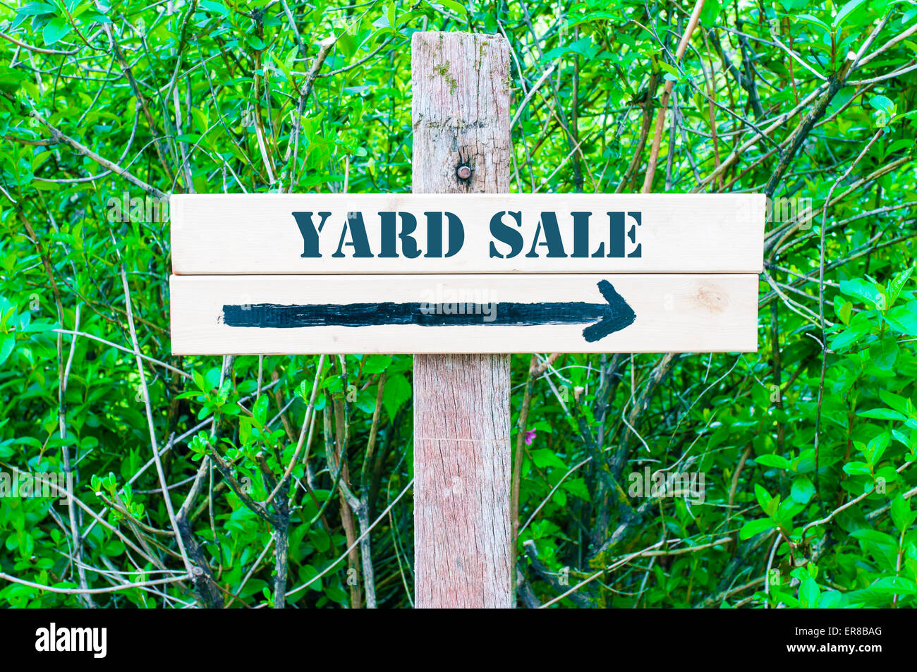 YARD SALE written on Directional wooden sign with arrow pointing to the right against green
