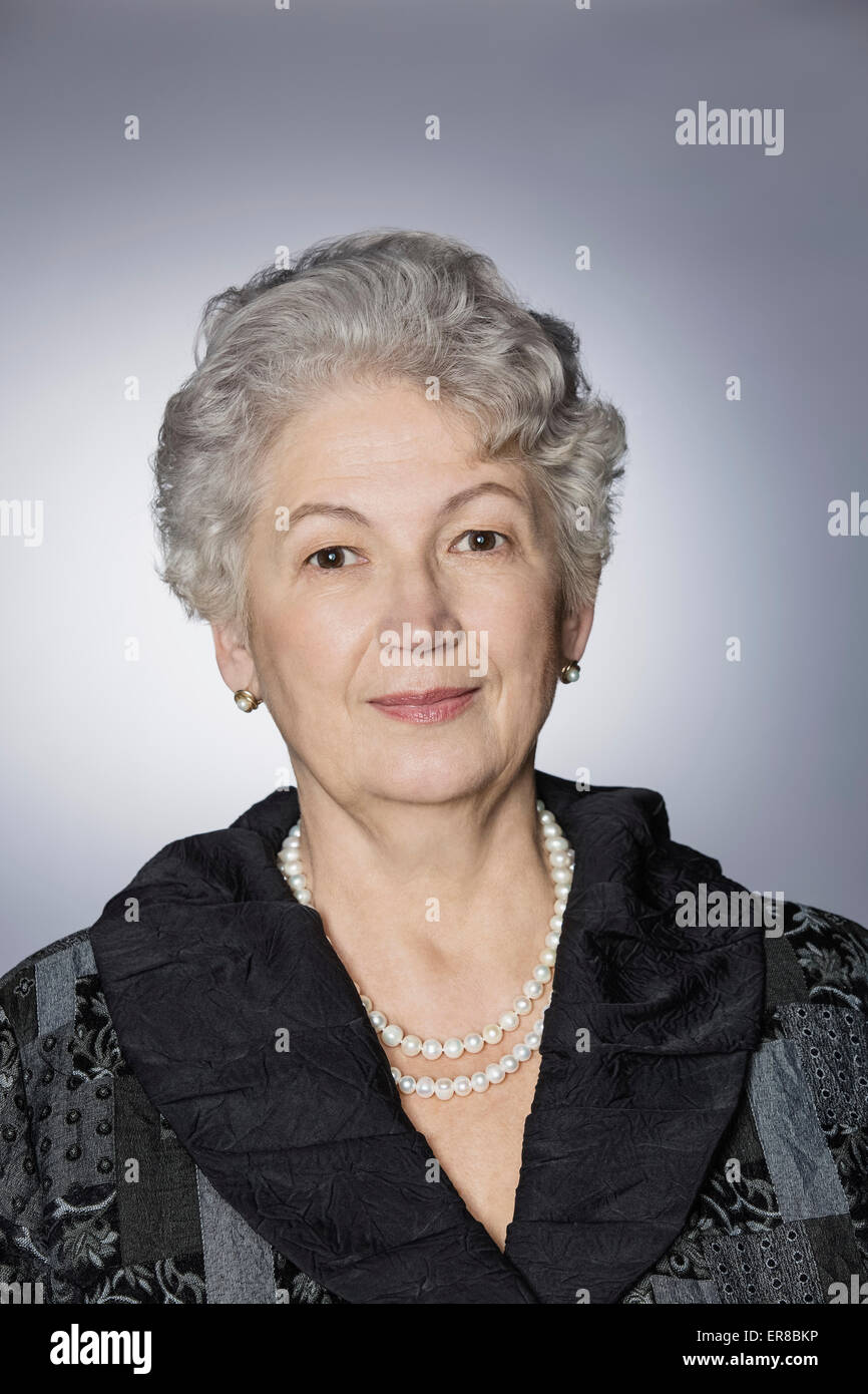 Portrait of confident senior woman over gray background Stock Photo