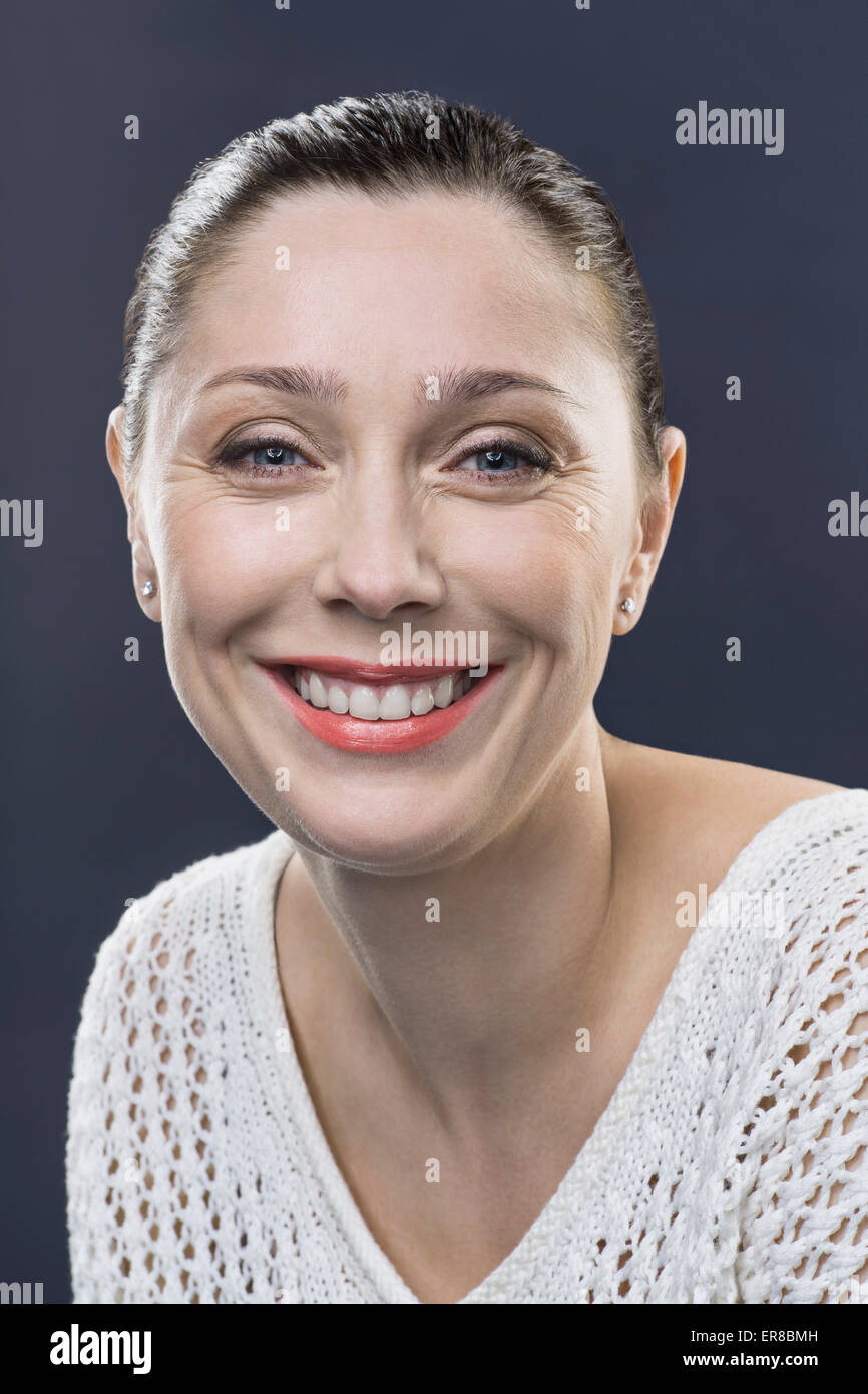 Close-up portrait of smiling mid adult woman over gray background Stock ...