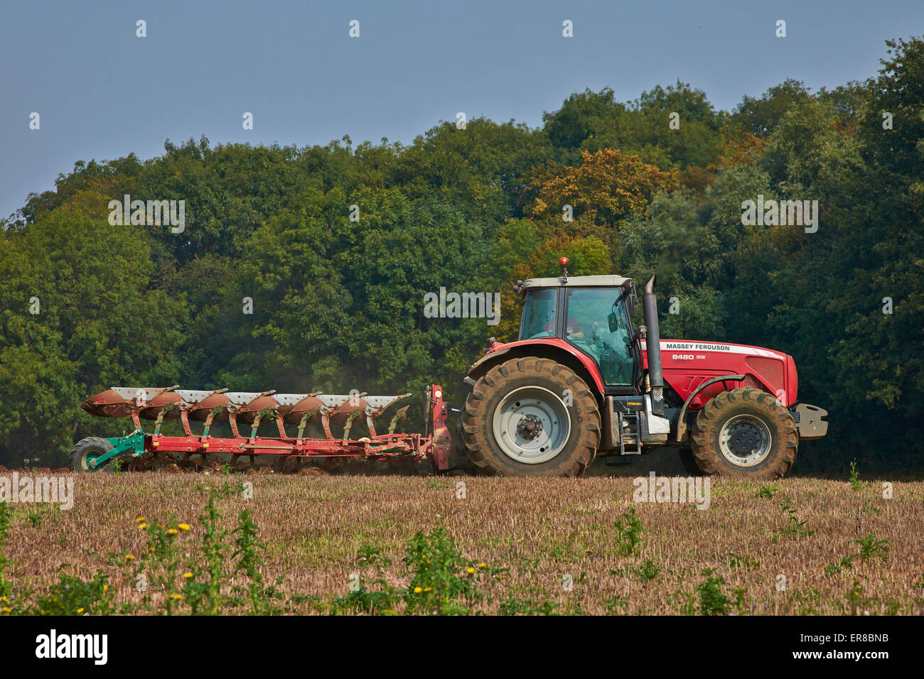 A red Tractor ploughing on Farmland In Kelvedon Essex, UK Stock Photo