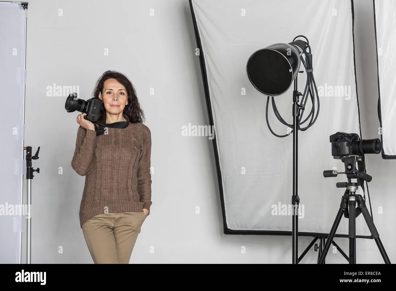 Portrait of mature female photographer with camera in photo studio Stock Photo