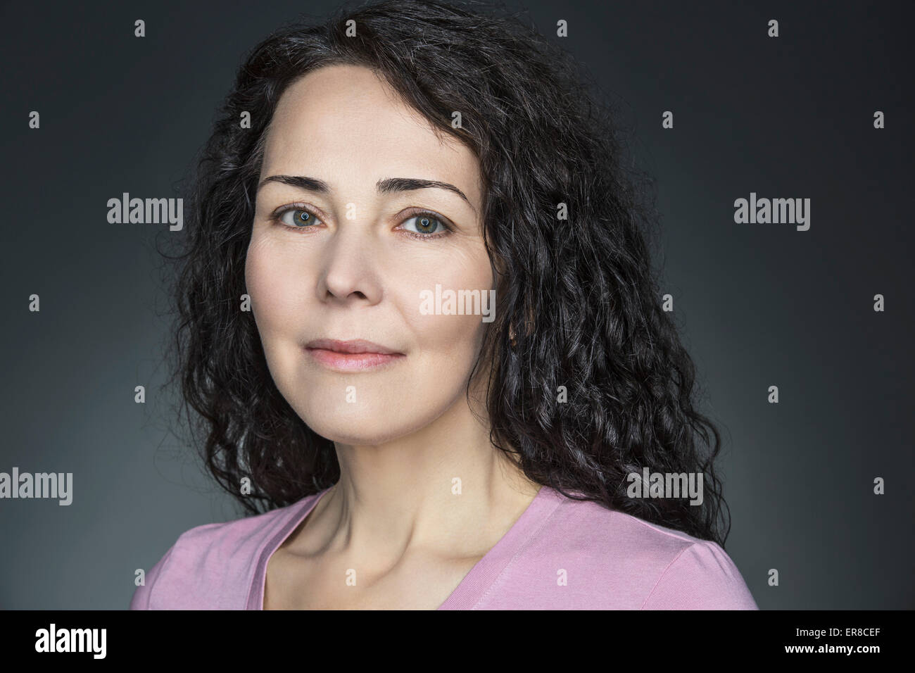 Close-up portrait of confident mature woman over gray background Stock Photo
