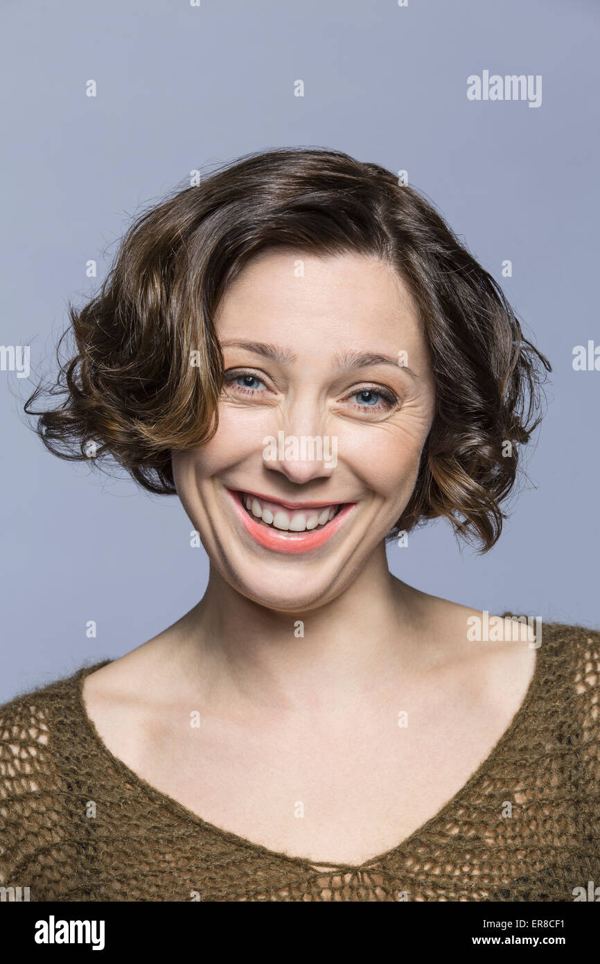 Portrait of smiling mid adult woman over gray background Stock Photo