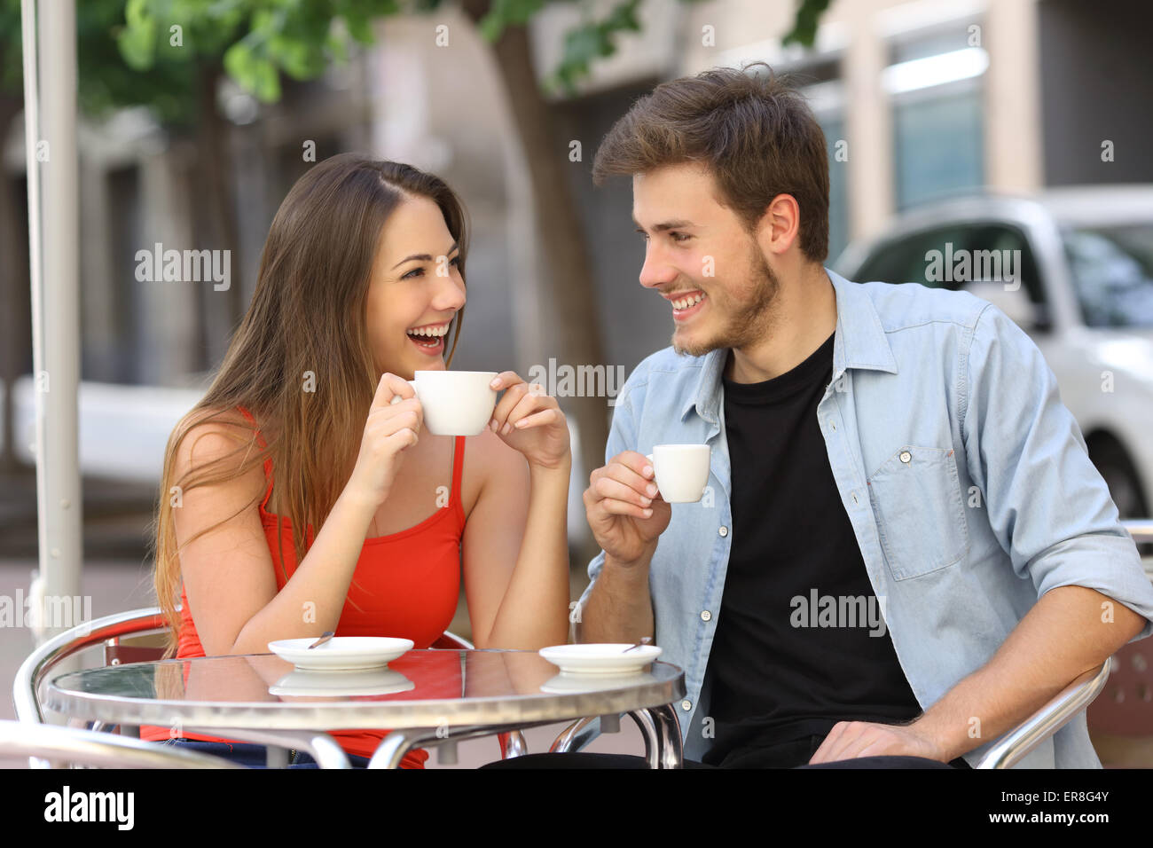Happy couple or friends flirting talking and drinking in a restaurant terrace Stock Photo