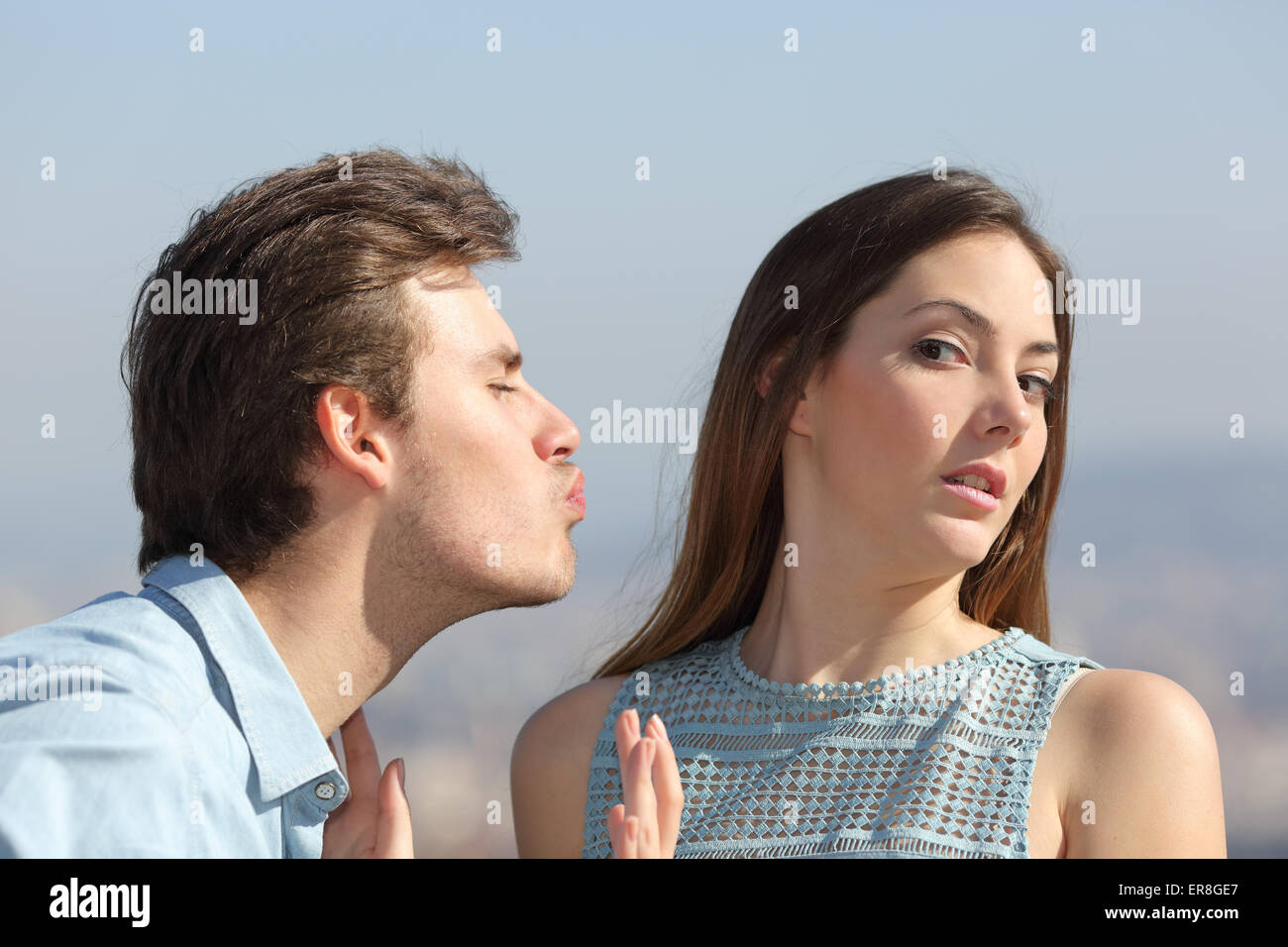 Friend zone concept with a man trying to kiss a woman and she rejecting him Stock Photo