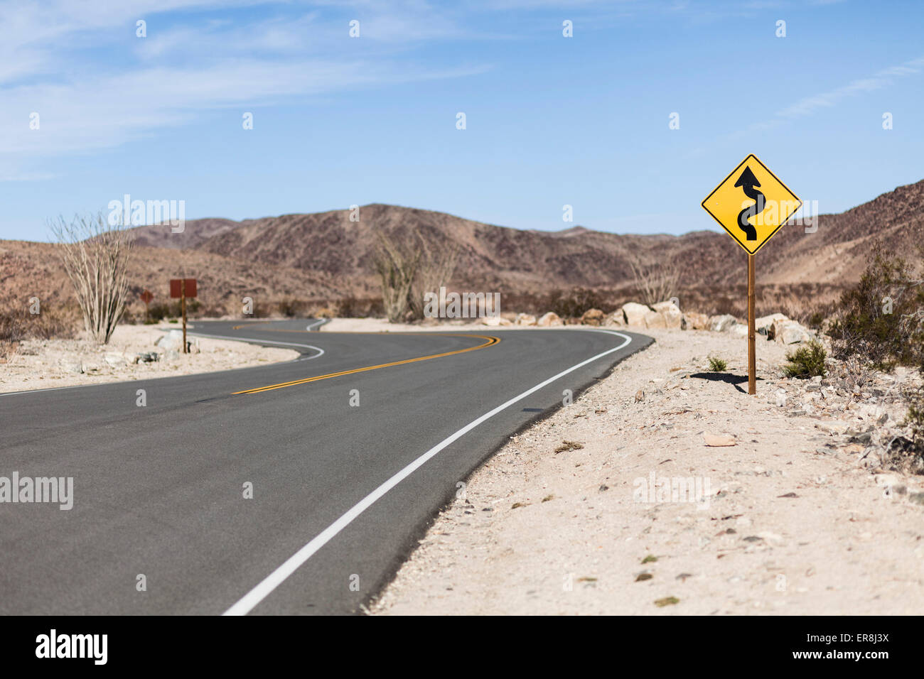 Directional sign by road at Joshua Tree National Park against sky Stock Photo