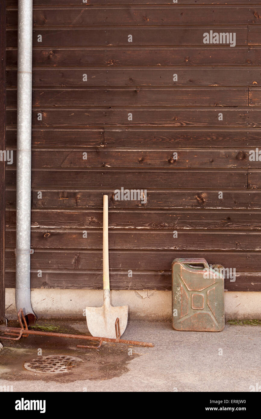 Shovel and container against wooden wall Stock Photo