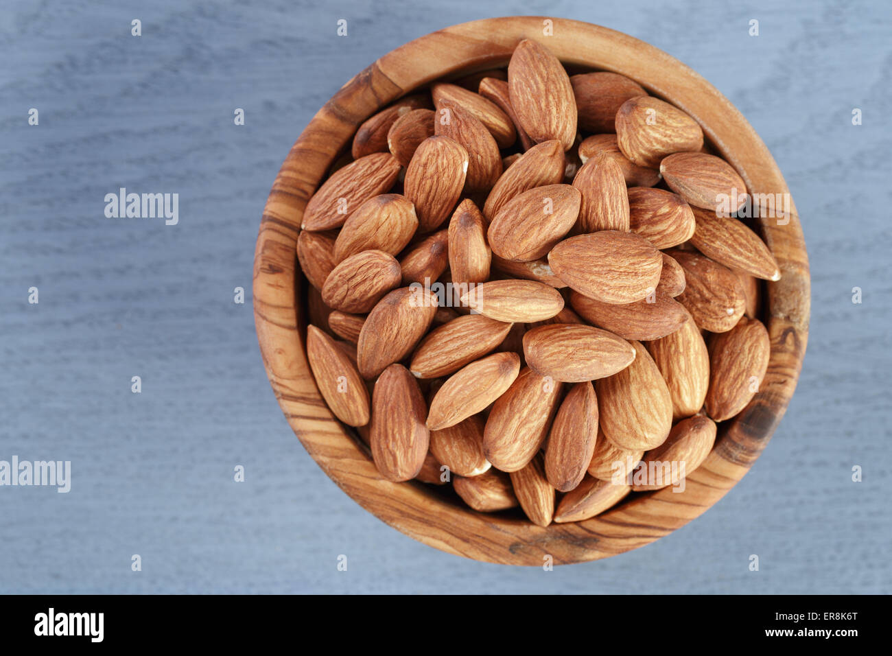 roasted almonds in bowl on blue wooden table Stock Photo