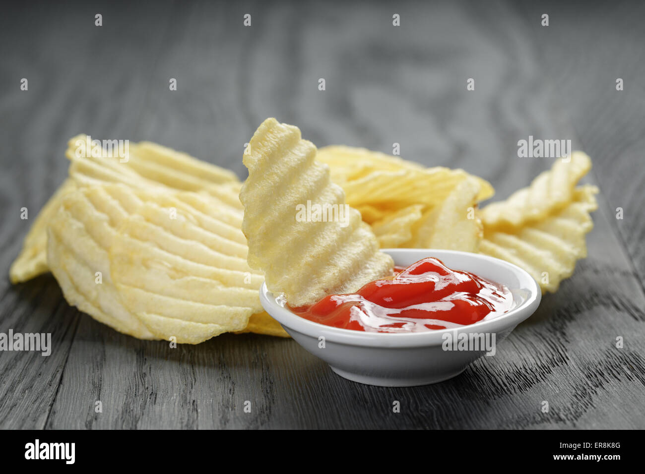 rippled organic chips wit tomato sauce on wooden table Stock Photo