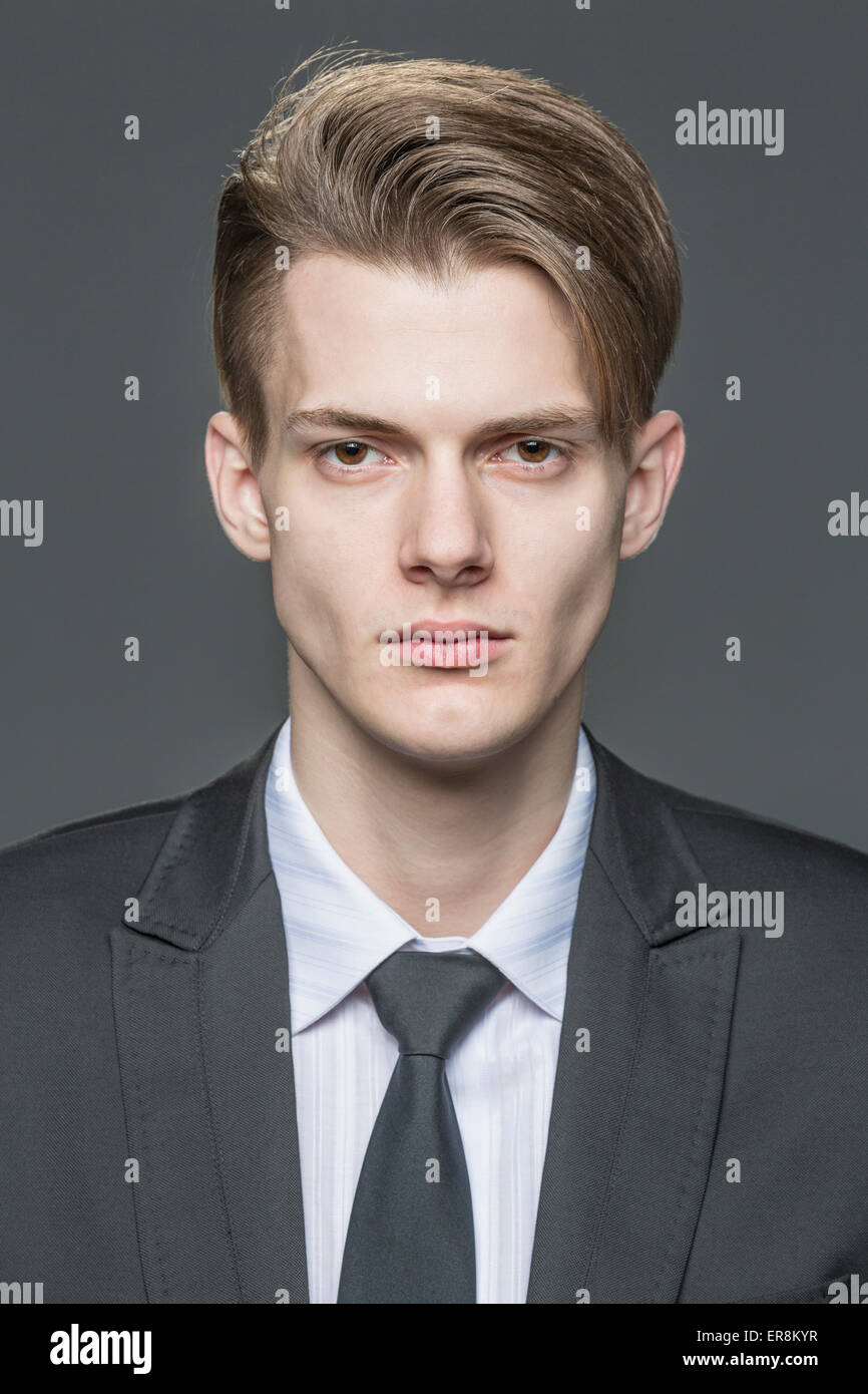 Portrait of confident young businessman over gray background Stock Photo