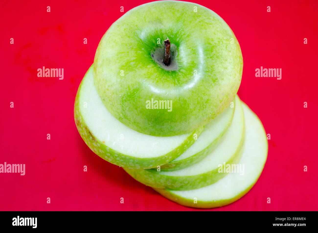Apple sliced in thin pieces against a red background Stock Photo