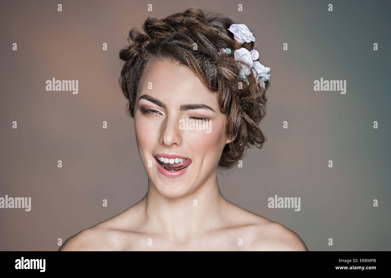 Portrait of playful young woman winking against colored background Stock Photo