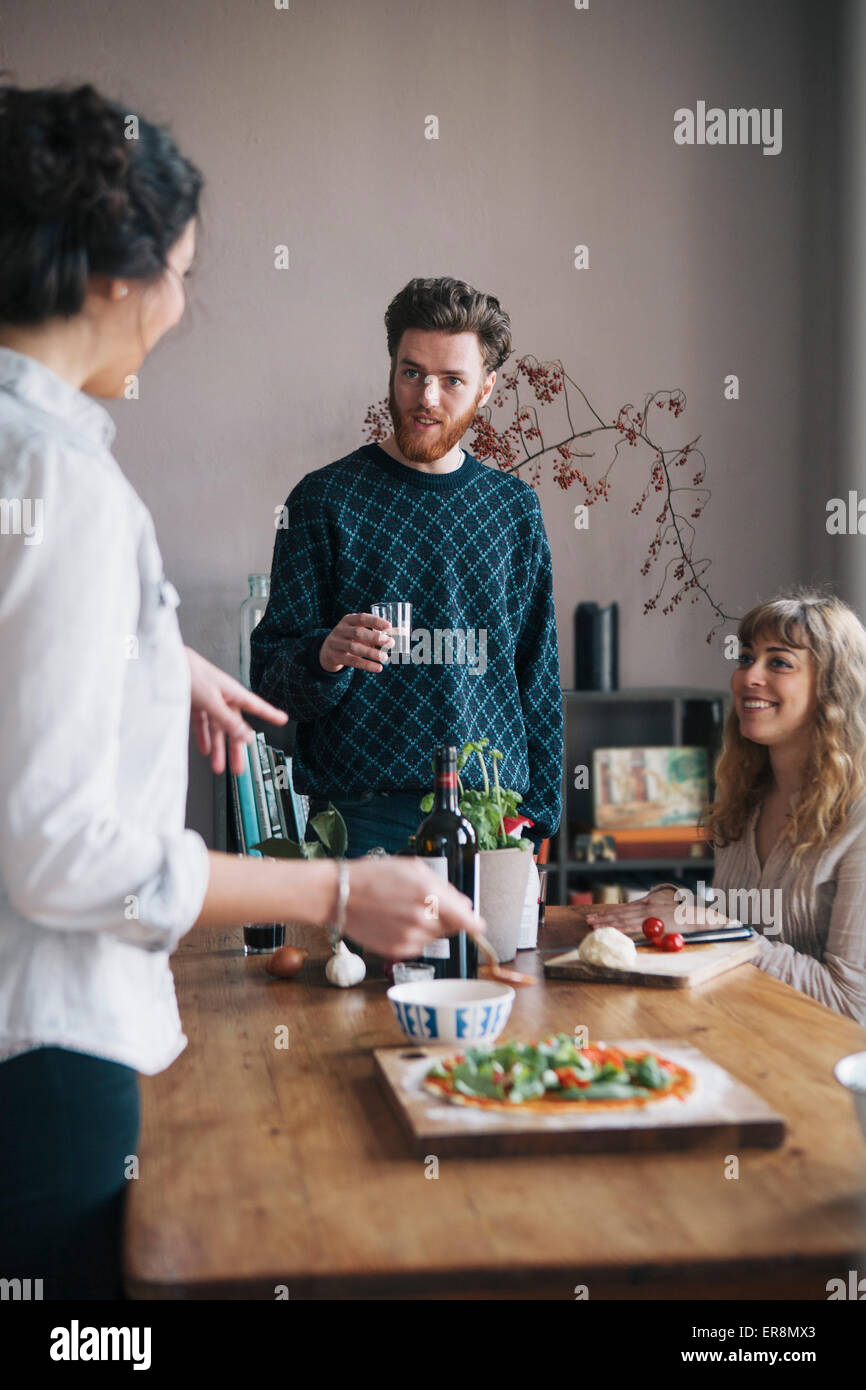 Young man with female friends talking while having breakfast at home Stock Photo