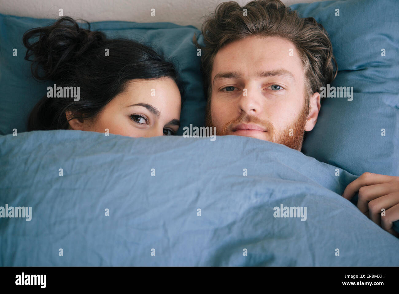 Portrait of loving young couple under duvet in bed Stock Photo