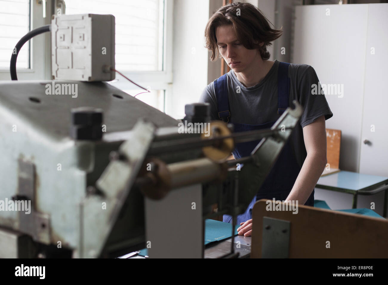 Young manual worker operating machine in factory Stock Photo