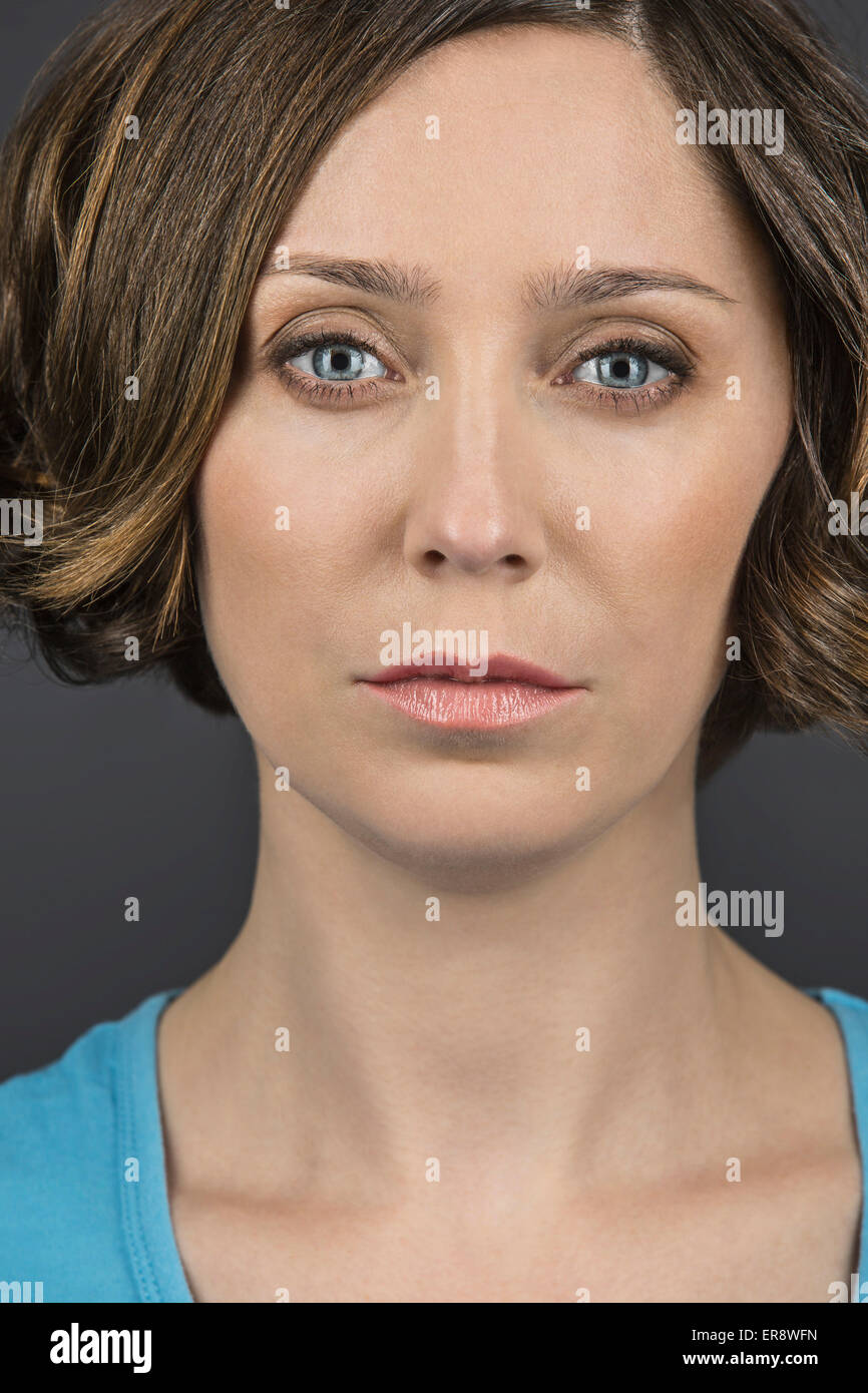 Close-up portrait of serious woman against gray background Stock Photo ...