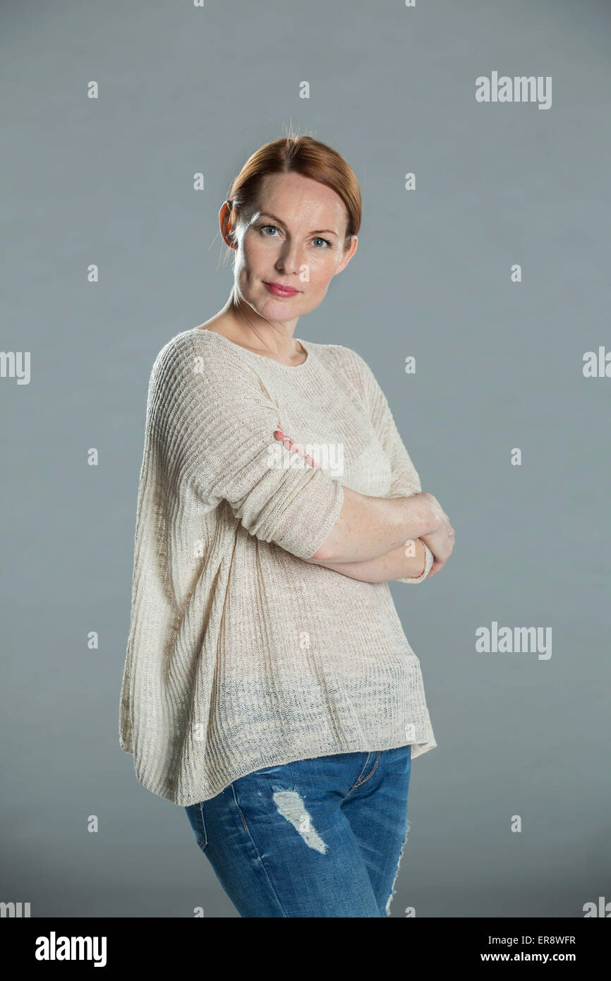 Portrait of confident woman standing arms crossed against gray background Stock Photo