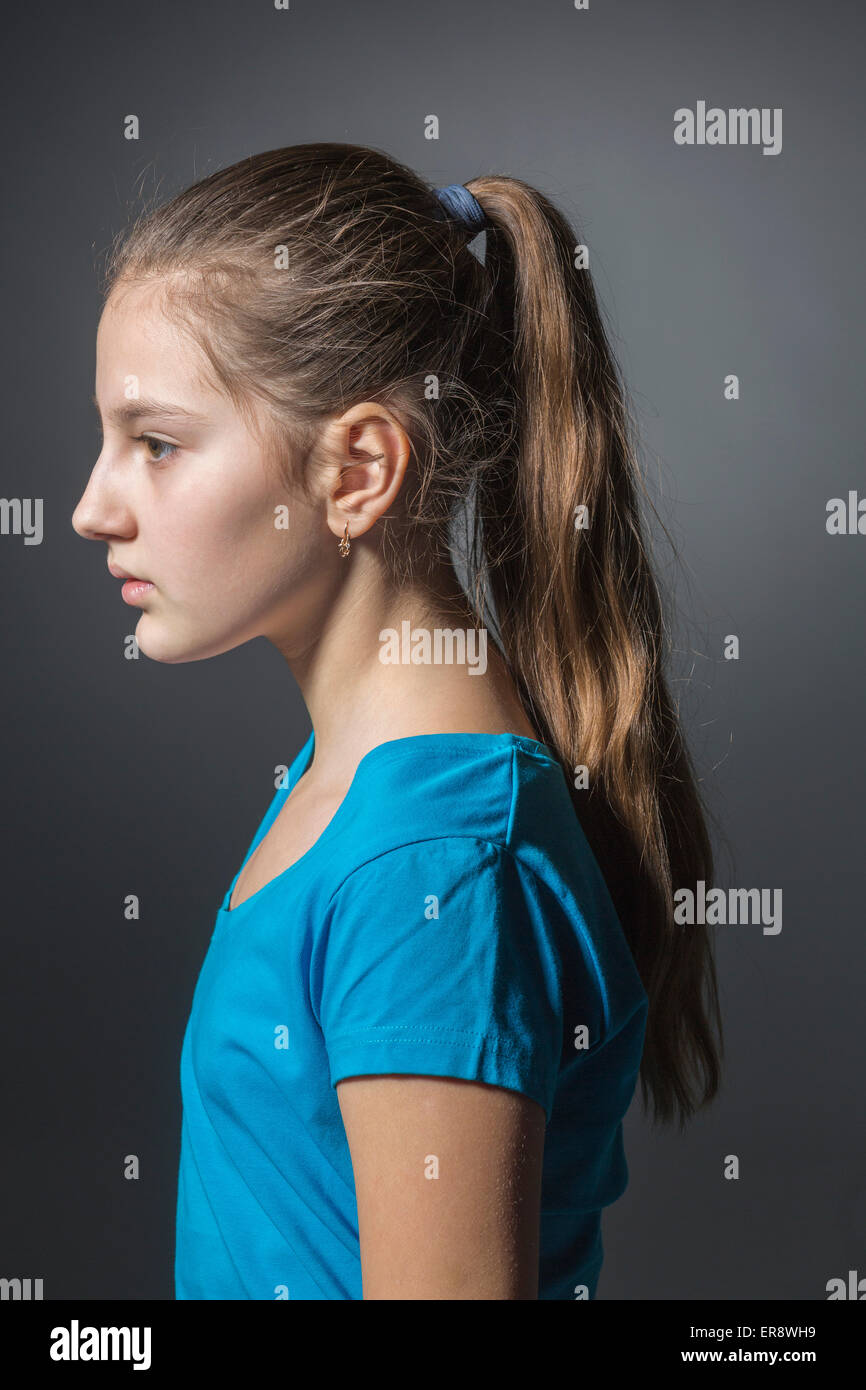 Side view of sad girl standing against gray background Stock Photo