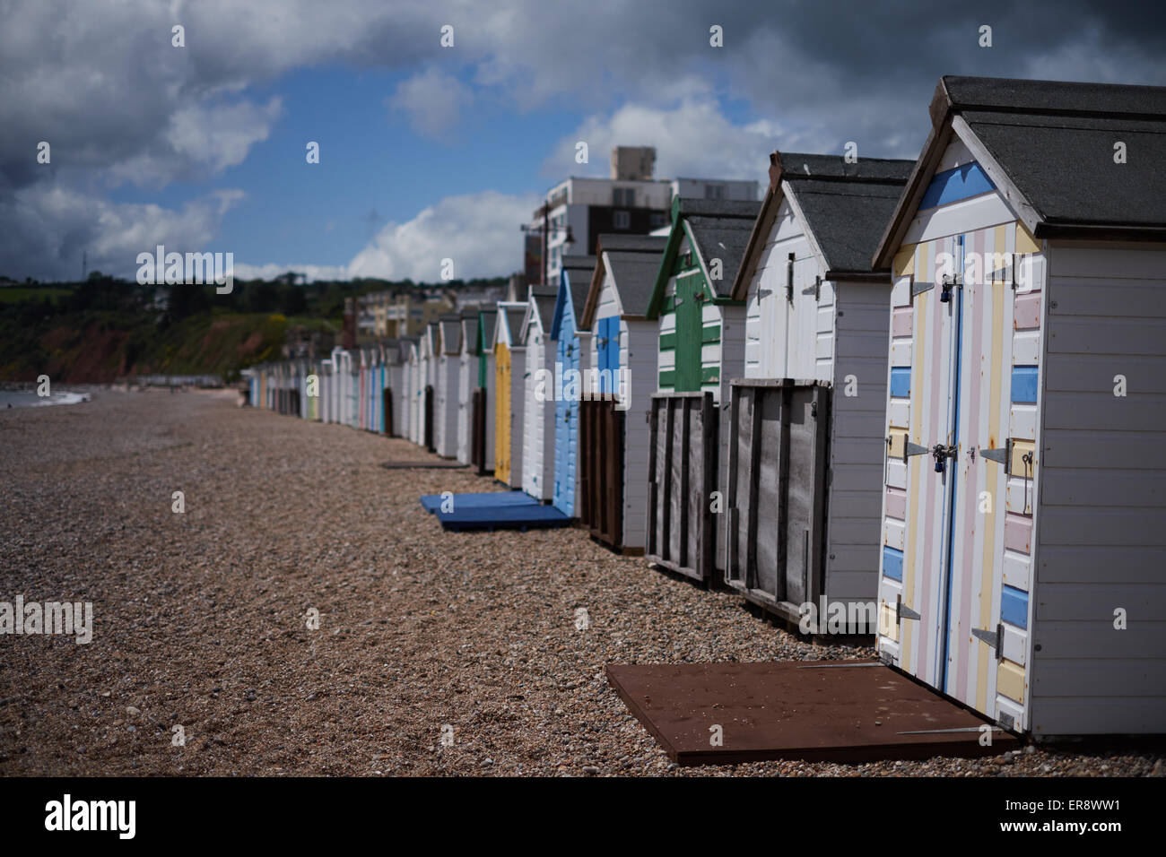 A row of colorful beach huts on a pebble beach in Seaton, Devon Stock